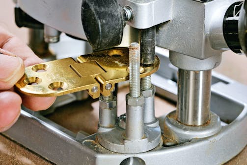 Indstil dybden på din overfræser: Vælg en position i revolveranslaget, læg dit emne (her et hængsel) på det, pres dybdestoppet ned til emnets overside, og lås stoppet Indstil dybden på din overfræser: Vælg en position i revolveranslaget, læg dit emne (her et hængsel) på det, pres dybdestoppet ned til emnets overside, og lås stoppet